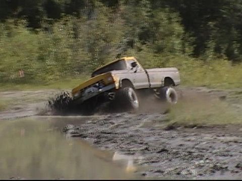 1979 Ford F-250 - A pickup truck navigates a muddy track, kicking up dirt and water.