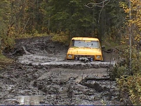 1979 Ford F-250 - A yellow 1979 Ford F-250 is seen struggling through a deep mud pit on an off-road trail.