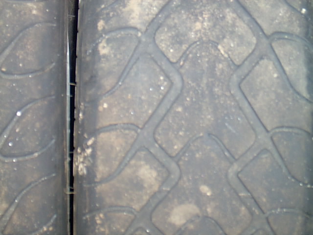 Extreme close-up of a worn tire tread with diamond pattern and dirt
