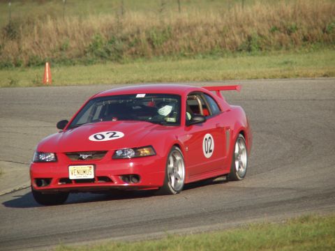 2000 Ford Mustang - Red 2000 Ford Mustang with racing numbers on a track.