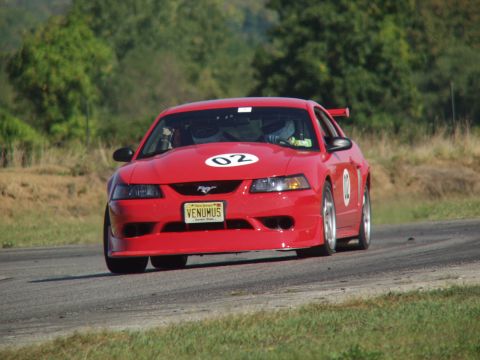 2000 Ford Mustang - Red 2000 Ford Mustang on a race track, displaying racing numbers 02 and 10.
