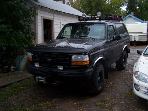 1996 Ford Bronco - This black Ford Bronco is equipped with a roof rack and off-road tires, suggesting it's ready for adventure.