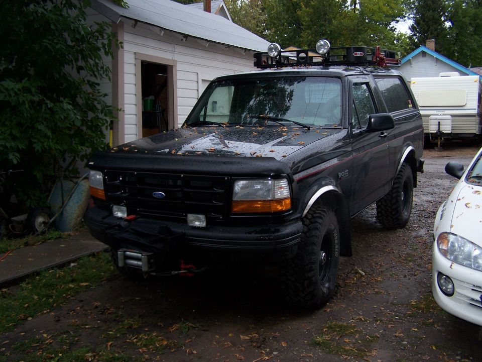 Black Ford Bronco with roof rack and off-road tires parked in driveway
