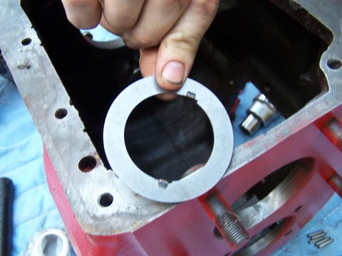 1979 Ford F-150 - Close-up of a hand holding a shim over an open transmission housing.