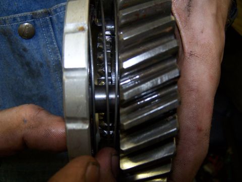1979 Ford F-150 - A mechanic inspects a transmission gear, focusing on the teeth and internal components.