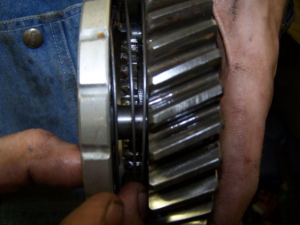 Close-up of a large metal gear with teeth, held by hands