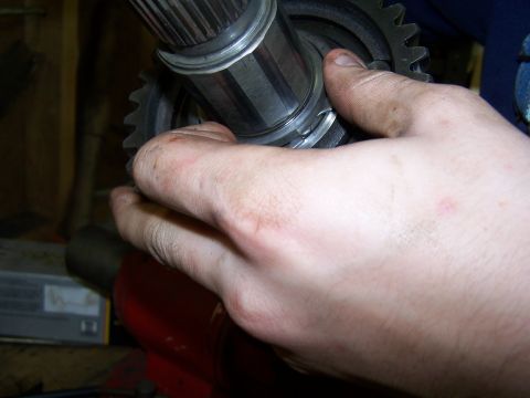 1979 Ford F-150 - A hand works on a metal gear and shaft assembly, likely a part of a vehicle's transmission system.