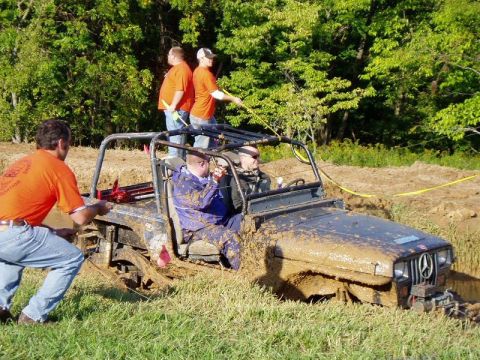 1992 Ford Bronco - People are trying to free a muddy Jeep that is stuck in a mud pit.