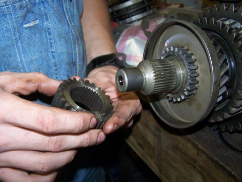 1979 Ford F-150 - Close-up of a transmission gear and shaft assembly being held by hands, with other parts visible in the background.