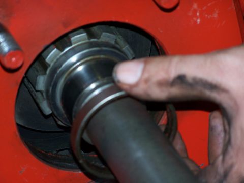 1979 Ford F-150 - A hand manipulates a mechanical part, showing a splined shaft and bearing within a red housing.