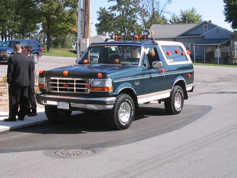 1992 Ford Bronco - A decorated 1992 Ford Bronco, possibly for a wedding, is seen from the front-three-quarter view. Another vehicle is visible in the backgrou…