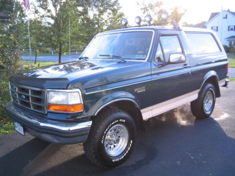 1992 Ford Bronco - A 1992 Ford Bronco is shown from a three-quarter front angle, with a white roof and tan side trim.