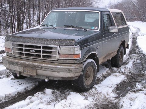 1992 Ford Bronco - This Ford Bronco navigates a challenging snowy and muddy path, with a Penn State University sticker visible on the windshield.