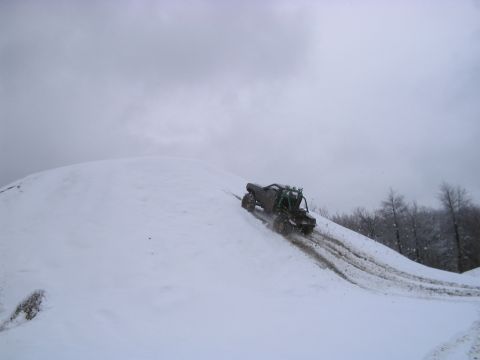 1992 Ford Bronco - An off-road vehicle navigates a steep, snow-covered incline, leaving tire tracks in its wake.