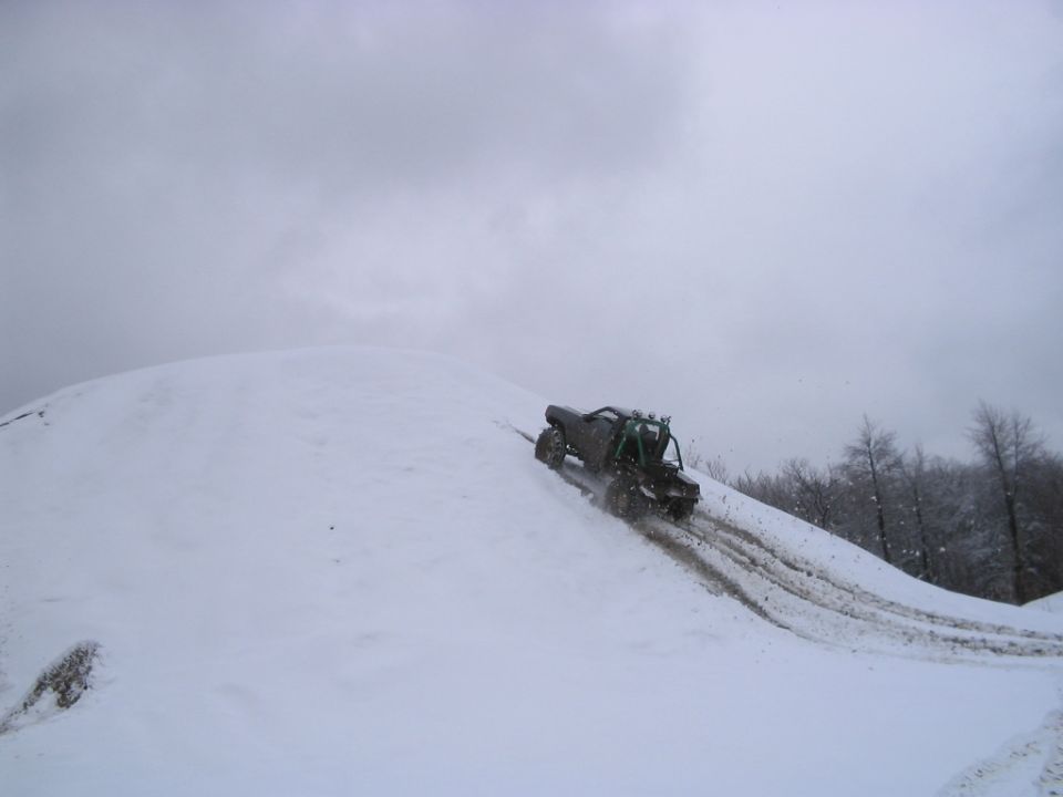 Off-road vehicle climbing a snowy hill, rear view