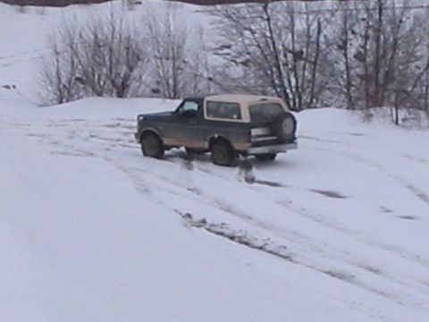 1992 Ford Bronco - A 1992 Ford Bronco navigates a snowy landscape with its spare tire visible on the back.