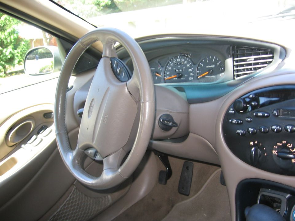 Tan Ford car interior, driver view of leather steering wheel, gauge cluster and radio