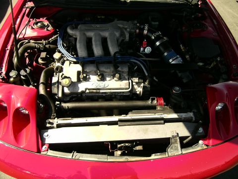 1993 Ford Probe - The engine bay of a red Ford Probe is visible, the V6 engine and radiator.