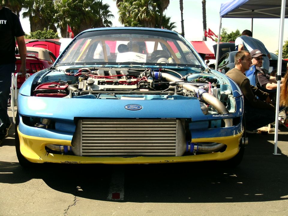 Front view of a blue and yellow car with hood open, showing engine and intercooler