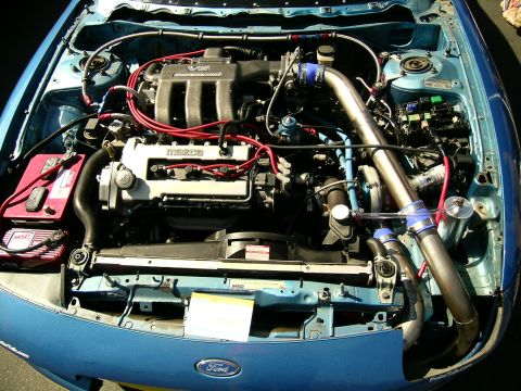 1993 Ford Probe - Engine bay of a blue car, a V6 engine with turbocharger modifications.