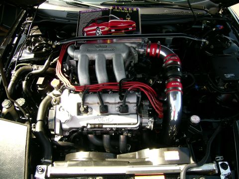 1993 Ford Probe - The engine bay of a 1993 Ford Probe GT, with a magazine detailing its '1993 Car of the Year' award placed on top.