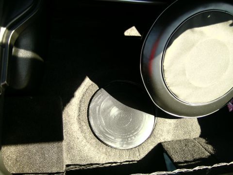 1993 Ford Probe - The trunk of a car shows a spare tire cover and a subwoofer, with sunlight casting shadows.