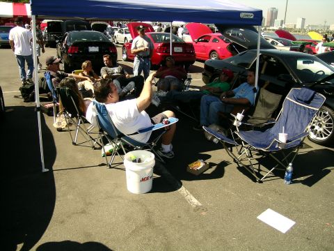 1993 Ford Probe - A group of people are gathered under a blue canopy, enjoying a car show event.