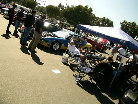 1993 Ford Probe - A group of people gather around a blue and yellow 1993 Ford Probe with its hood open at an outdoor car event.