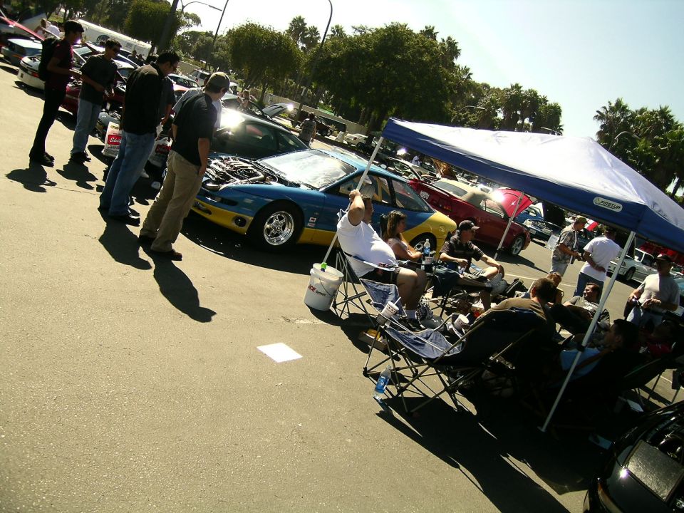 1993 Ford Probe, blue and yellow, hood open, parked at an outdoor event with people around