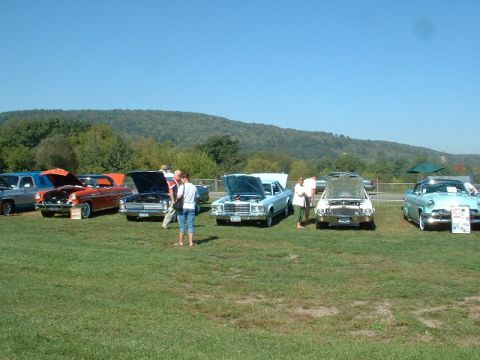 1978 Ford Mustang II - A light blue coupe is displayed with its hood open at an outdoor car show, alongside other vehicles.
