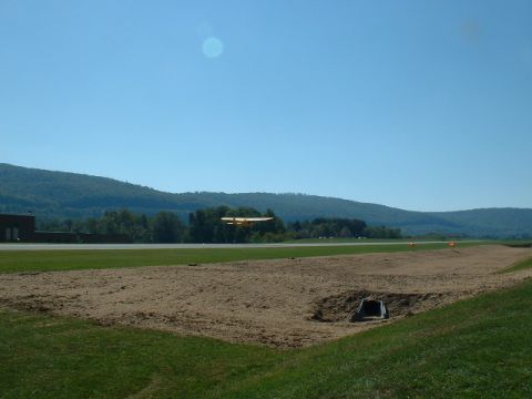 1978 Ford Mustang II - Airplane flying over a field with mountains in the distance.