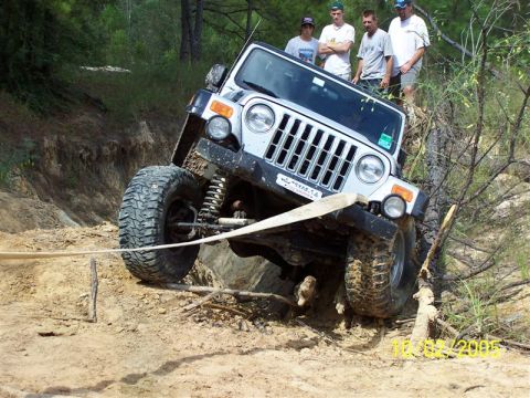 1987 Ford Bronco - A Jeep Wrangler navigates a challenging off-road course with onlookers watching.