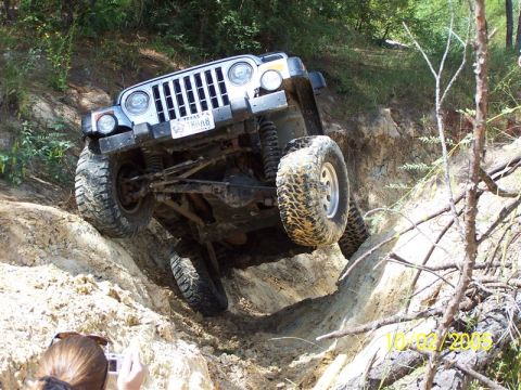 1987 Ford Bronco - A silver Jeep Wrangler TJ is captured mid-climb on a challenging off-road trail.