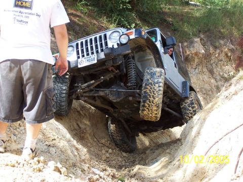 1987 Ford Bronco - Off-road Jeep Wrangler navigates a challenging dirt trail with steep inclines.