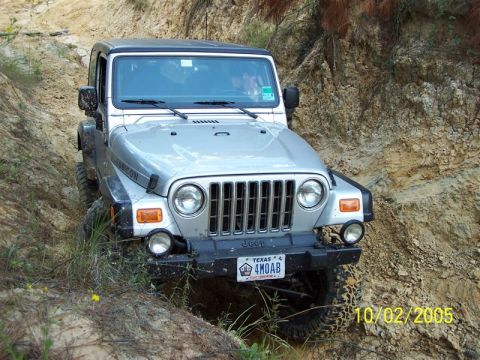 1987 Ford Bronco - A Jeep Wrangler Rubicon navigates a steep, muddy trail.