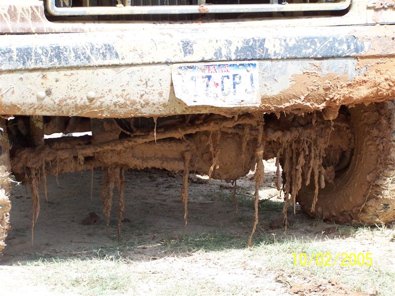 Truck undercarriage and front bumper caked in thick dried mud with partial license plate