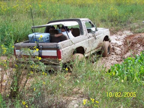 1987 Ford Bronco - This 1987 Ford Bronco is deep in the mud, with people inside enjoying the off-road adventure.