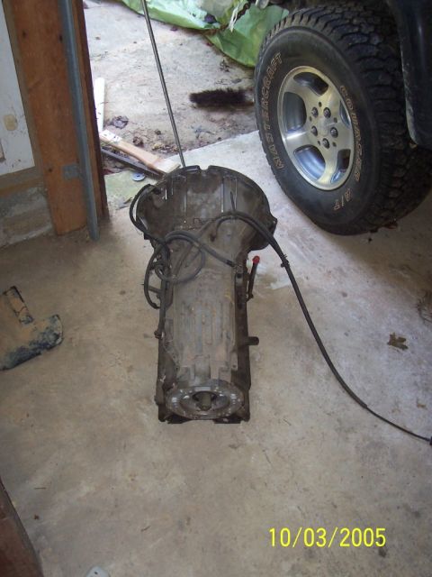 1994 Jeep YJ - A transmission is shown on a concrete floor, with a vehicle tire visible in the background.