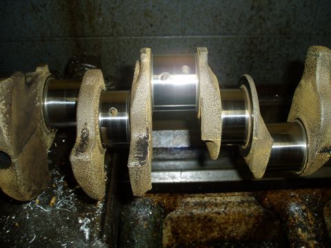 1969 Ford Bronco - A crankshaft is shown with its journals and counterweights, resting on a machine.