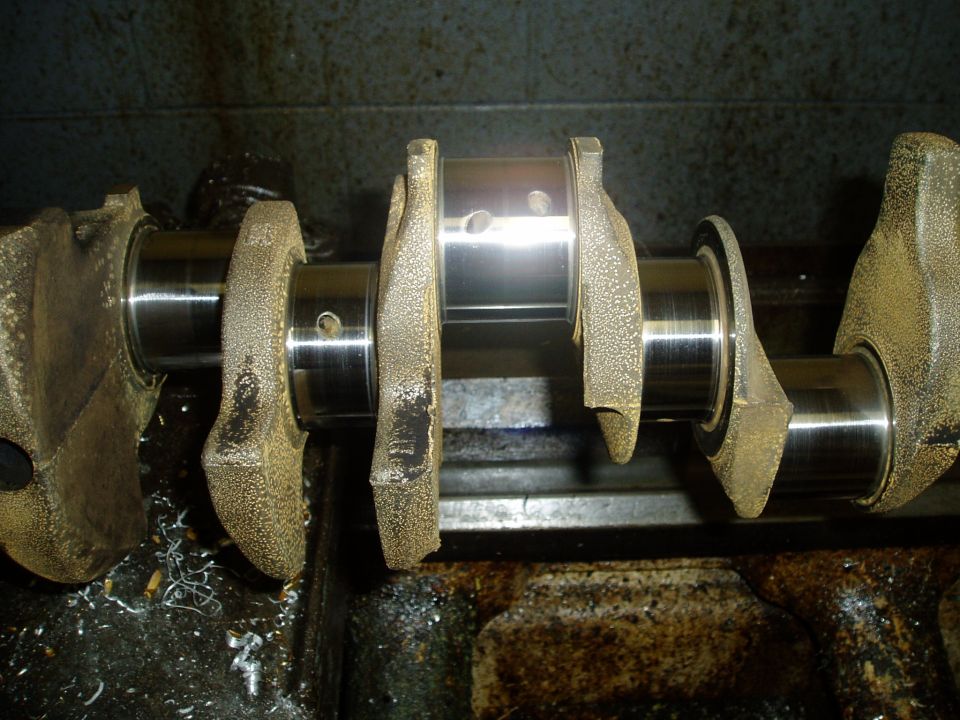 Close-up of a crankshaft with metal shavings on the surface