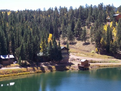 1972 Ford Ranchero - A lake is surrounded by a dense pine forest and several cabins on a sunny day.