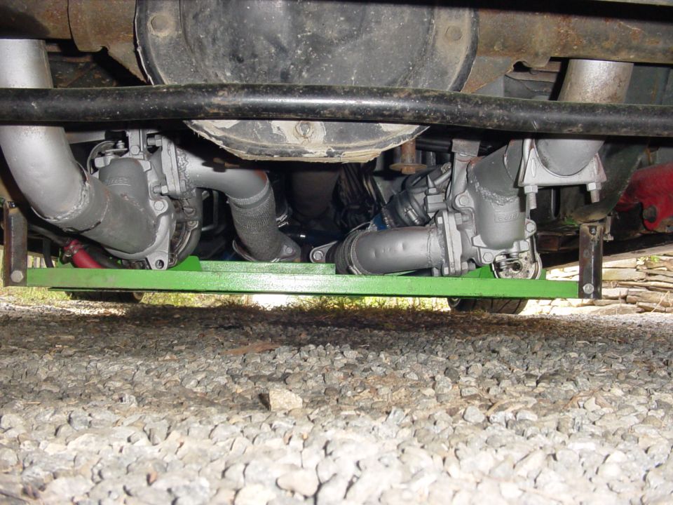 twin turbochargers and exhaust piping mounted on a green bracket under a vehicle