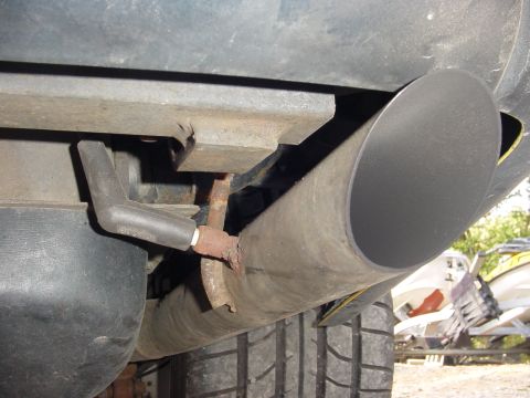 1995 Ford Mustang - Underside view of a vehicle's exhaust pipe and tire, with a jet ski visible in the background.
