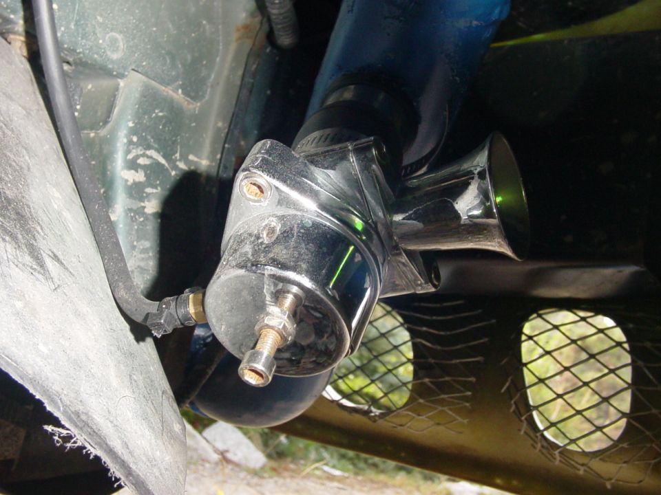 chrome air horn mounted on a vehicle, with blue hose and green painted metal