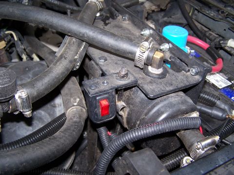 1996 Ford Bronco - Close-up view of engine components, including a red toggle switch and various hoses and wiring.