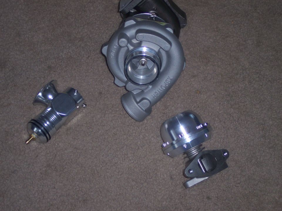 XS-Power turbocharger, polished blow-off valve, and external wastegate laid out on carpet