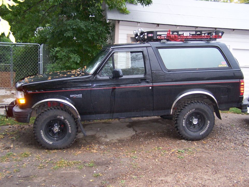 Black 1996 Ford Bronco with a roof rack and off-road tires parked outside