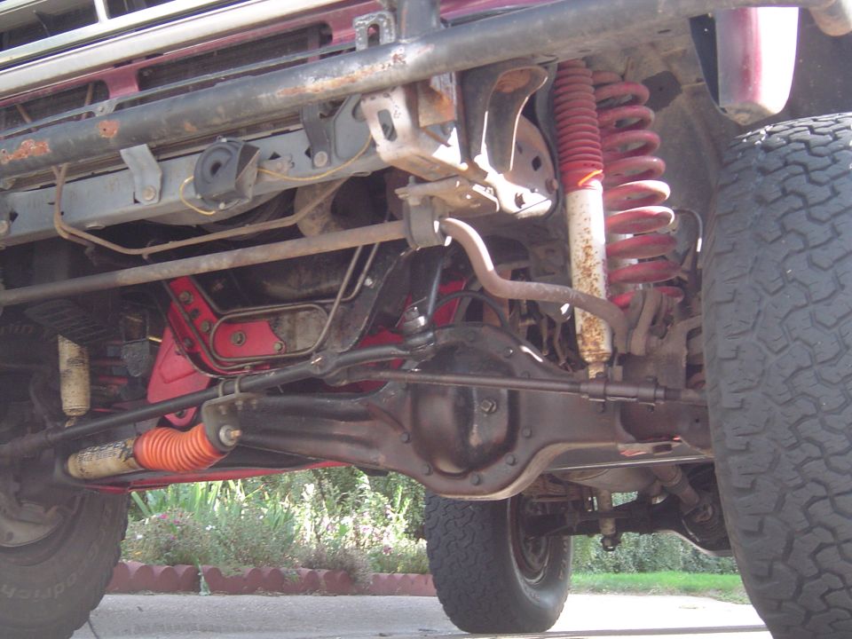 Undercarriage of a red SUV with visible suspension components, differential, and tires