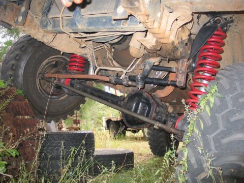 1995 Ford Bronco - The undercarriage of a modified off-road vehicle shows heavy-duty suspension components and large tires.