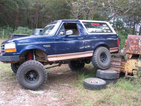1995 Ford Bronco - This modified Ford Bronco is positioned on uneven terrain, with its tires stacked on top of each other.
